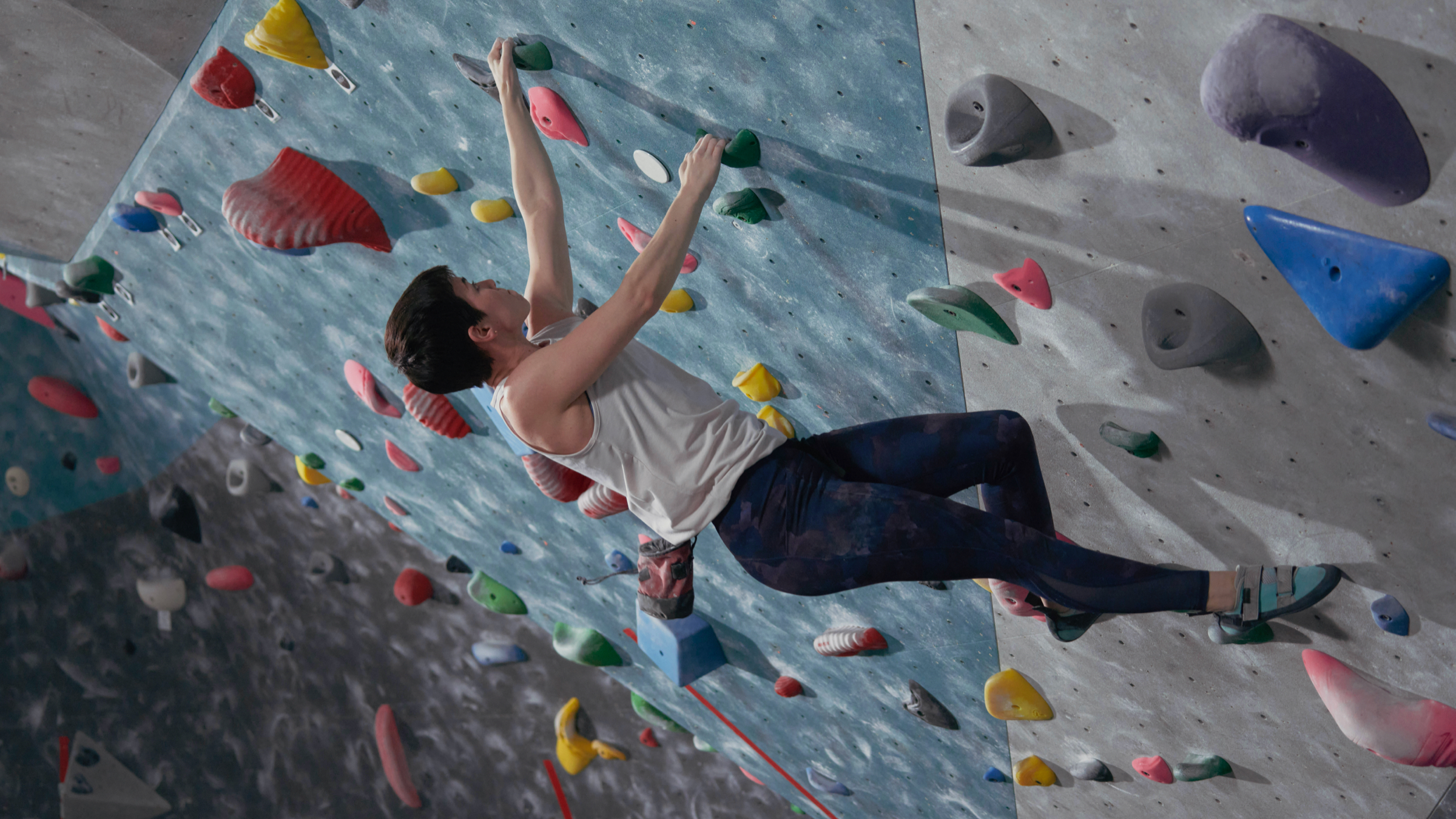 Woman in action shot climbing an indoor practice wall