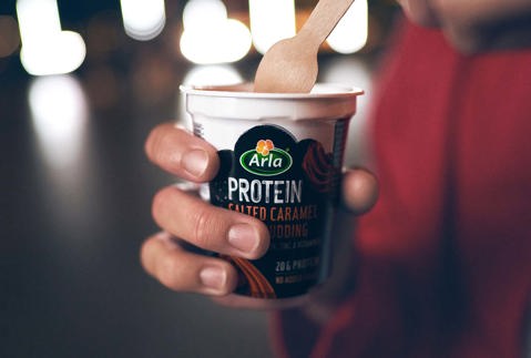 Kobieta w czerwonej bluzce jedząca pudding drewnianą łyżką